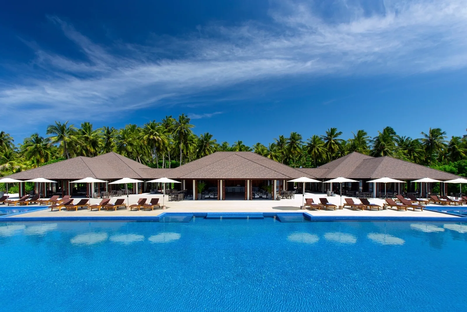 Resort pool and thatched pavilions lined with palms
